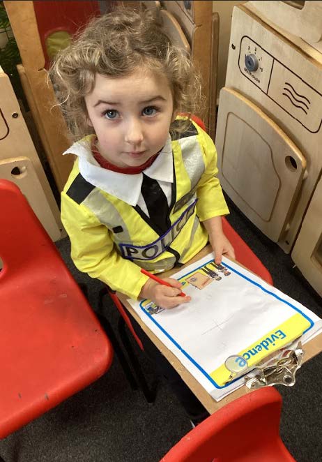 A young pupil dressed a police officer writing on paper on a clipboard.
