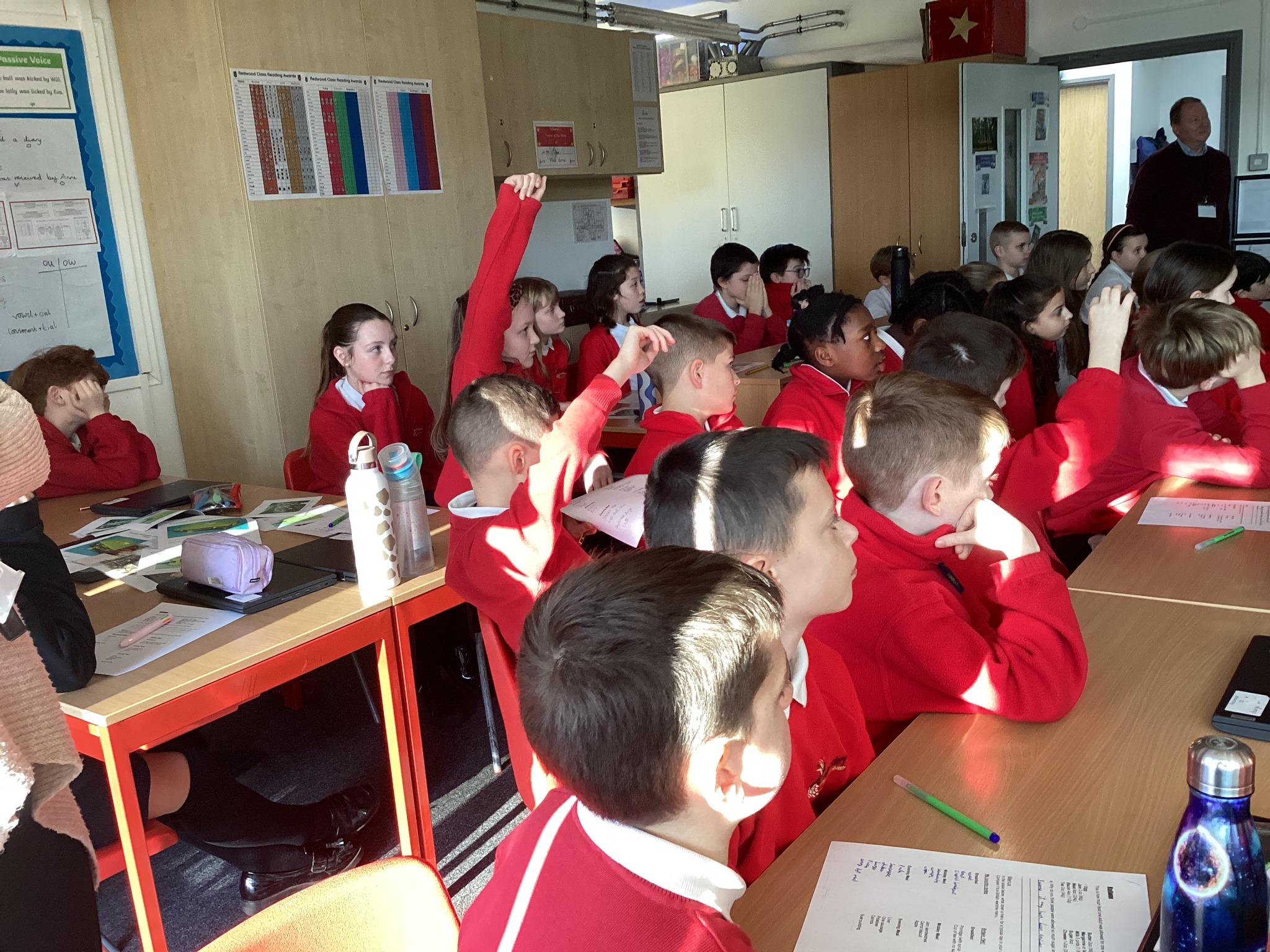 Students at desks with their hands up