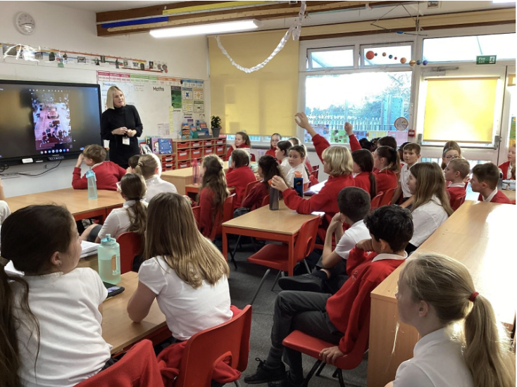 Students in a classroom listening to a talk from an adult