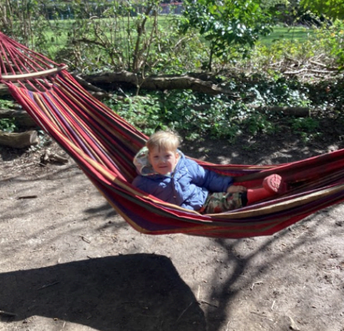 A young child laying in a hammock outdoors